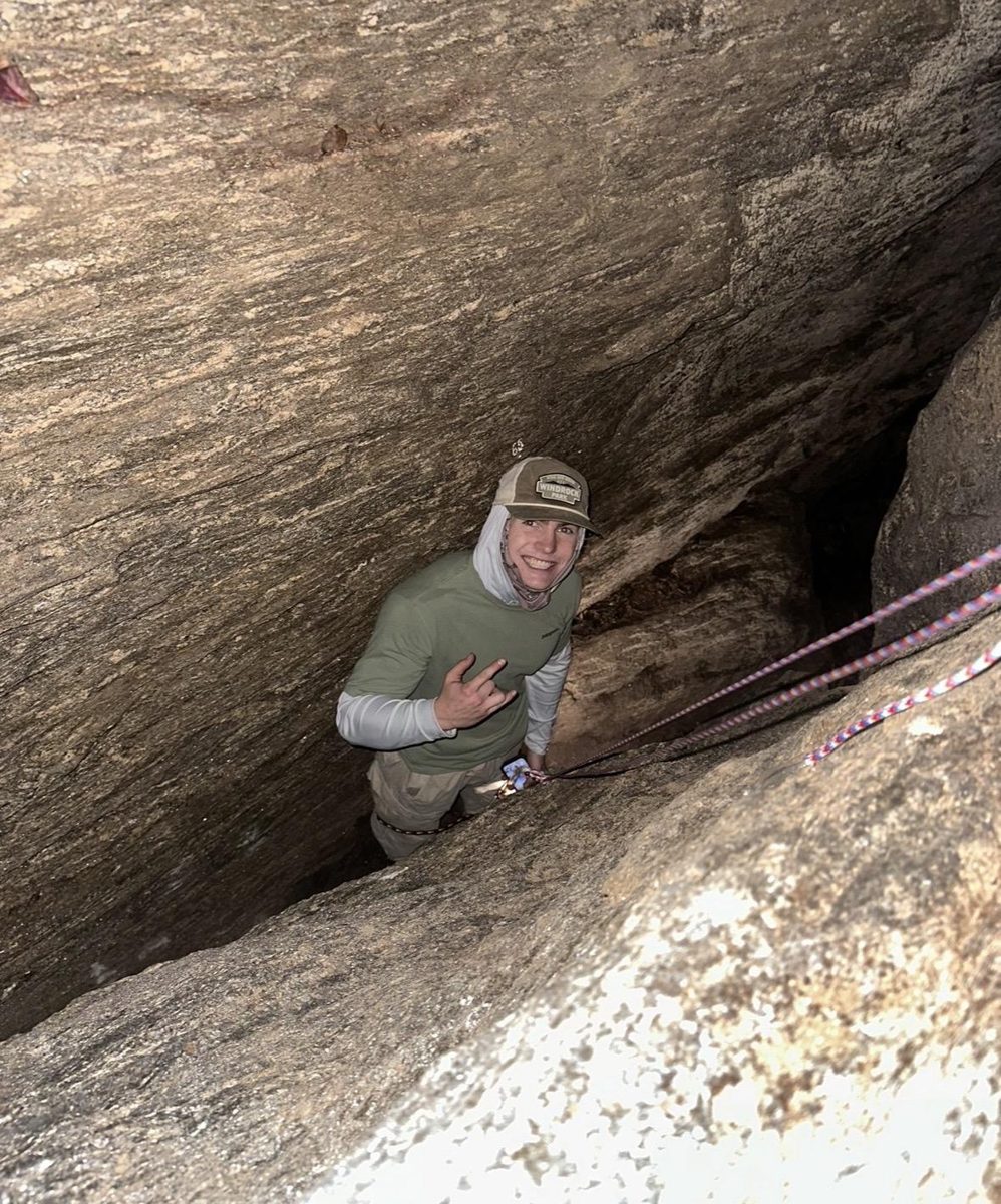 Jack grinning while climbing through a cave