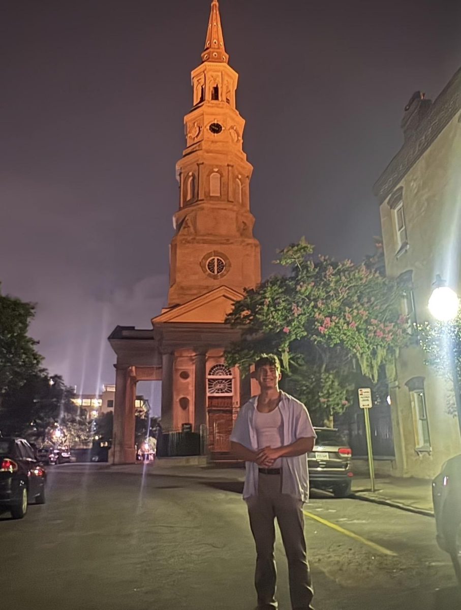 Jack Fowles at night on a downtown Charleston street, St. Philip's Church steeple lit warmly behind him